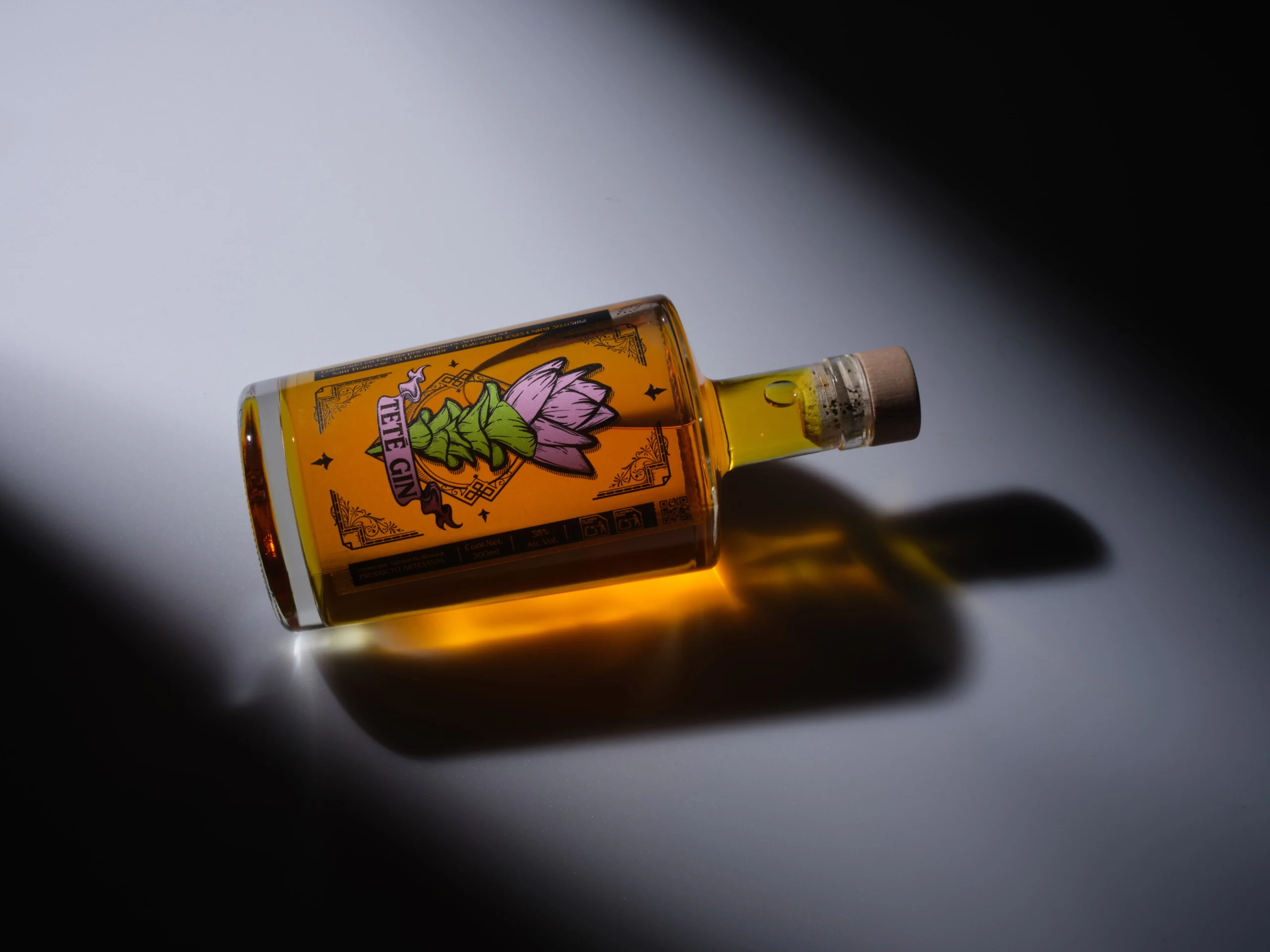 Botella de Teté Gin sobre fondo iluminado destacando su color ámbar y etiqueta artística.